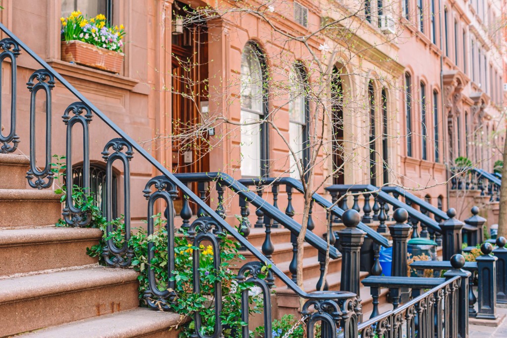 Classic Manhattan brownstone stoop with wrought-iron railing and spring flowers