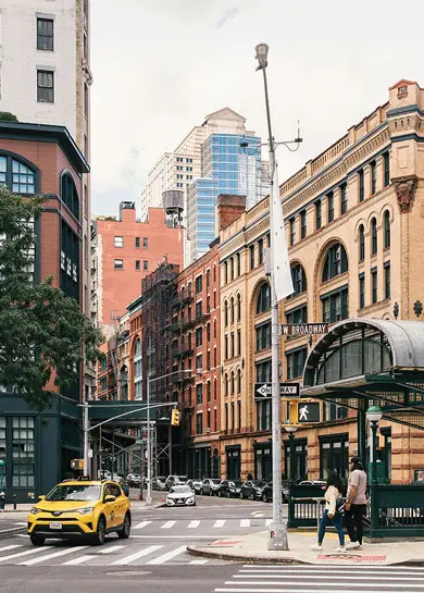 West Broadway street scene in Tribeca with yellow taxi and subway entrance